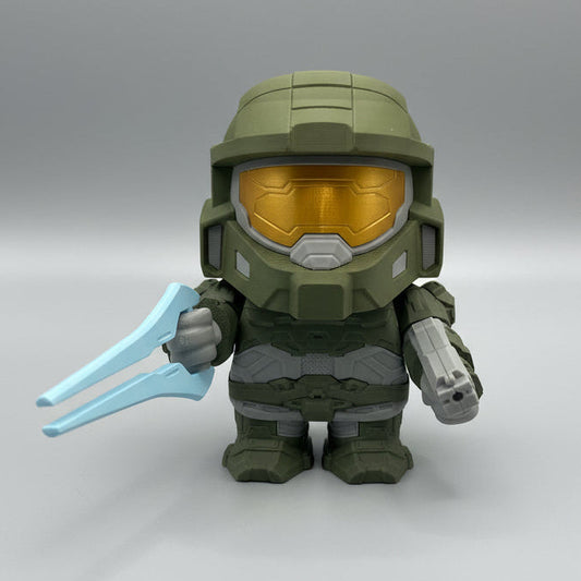 Toy figure of a character with green helmet and gold visor on a white surface.
